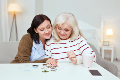 senior woman and a caregiver playing puzzle